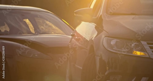 Car accident in the city. View of two modern cars crashed standing stuck on the road at sunset. Traffic collision. photo