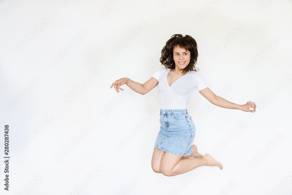 close up photo of a happy brunette in white blouse and denim skirt jumping in the air close up photo of a happy brunette in white blouse and denim skirt jumping in the air