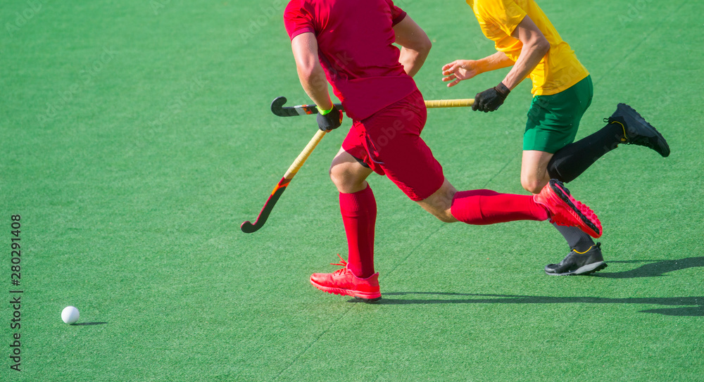 Obraz premium Two field hockey player, fighting for the ball on the midfield during an intense match on artificial grass