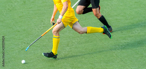 Two field hockey player  fighting for the ball on the midfield during an intense match on artificial grass