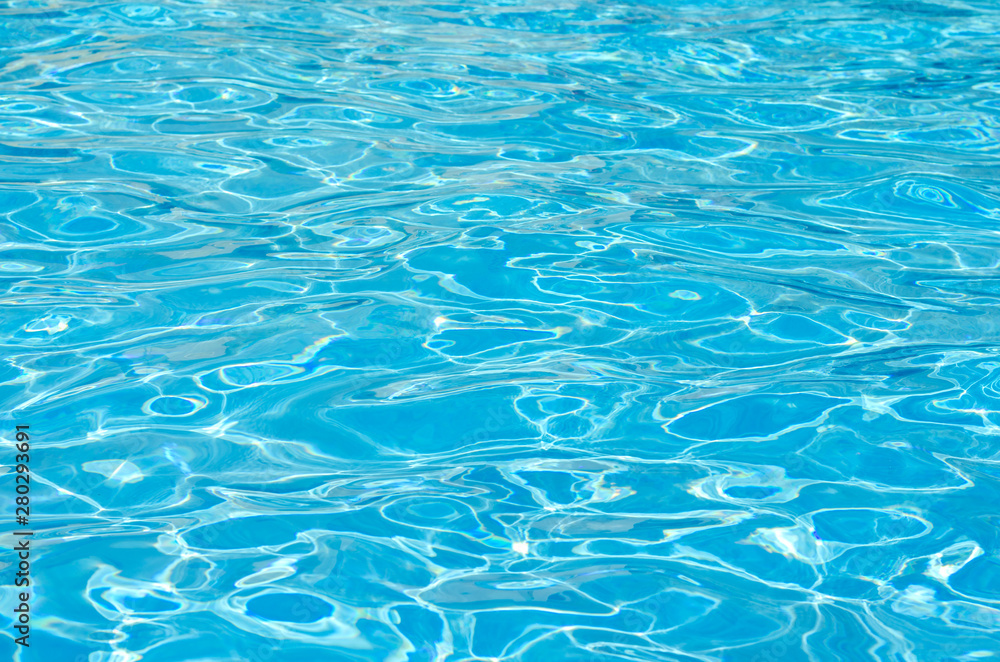 Waves and clear blue water surface  in the swimming pool of a resort .