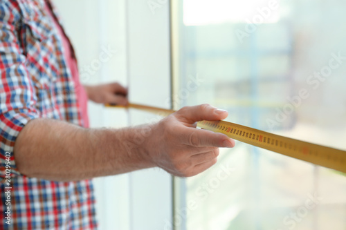 Man measuring window, closeup view. Construction tool