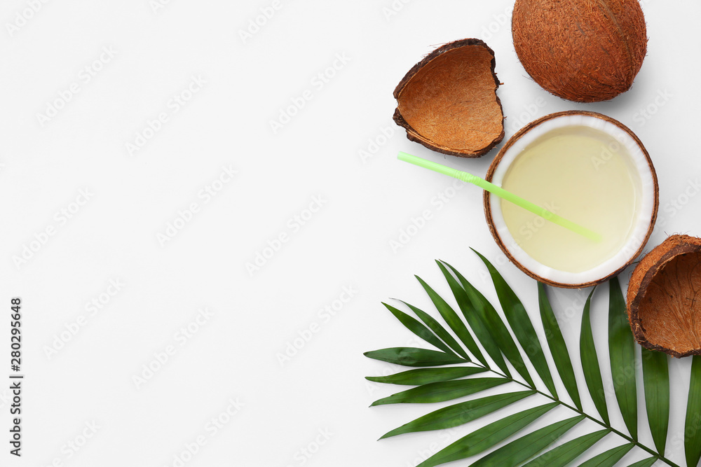 Composition with drink in half of coconut and palm leaf on white background, top view Composition with drink in half of coconut and palm leaf on white background, top view