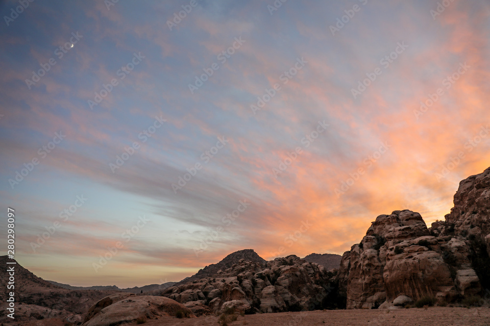 A brilliant sunset over the redrock camp at the base of a cliff in Petra Jordan. 