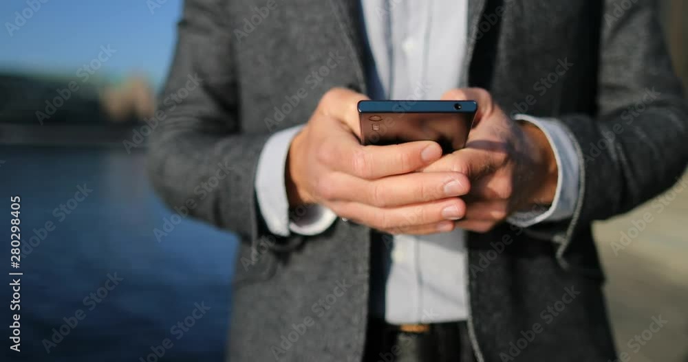 Mobile Phone closeup- Professional business man using smartphone walking in city. Businessman in suit using smartphone app. 59.94 FPS