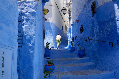 A local woman walks the streets of an old medina in a blue city Chefchaouen in Morocco. © vadim_ozz