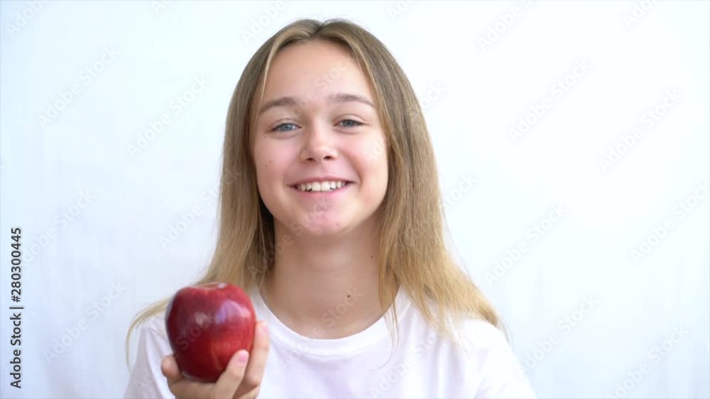 Сute attractive young blond woman in white shirt takes a red apple Сute attractive young blond woman in white shirt takes a red apple