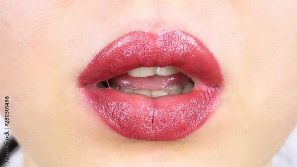 Extreme close-up of lips of a young woman. Woman paints her lips with bright lipstick for makeup. Women's morning makeup Extreme close-up of lips of a young woman. Woman paints her lips with bright lipstick for makeup. Women's morning makeup