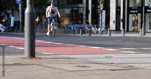 Street view of people walk cross the road, cyclist and rider ride bicycle and E-scooter on bicycle lane at pedestrian crossing and blur background of cityscape on Königsallee in Düsseldorf, Germany.