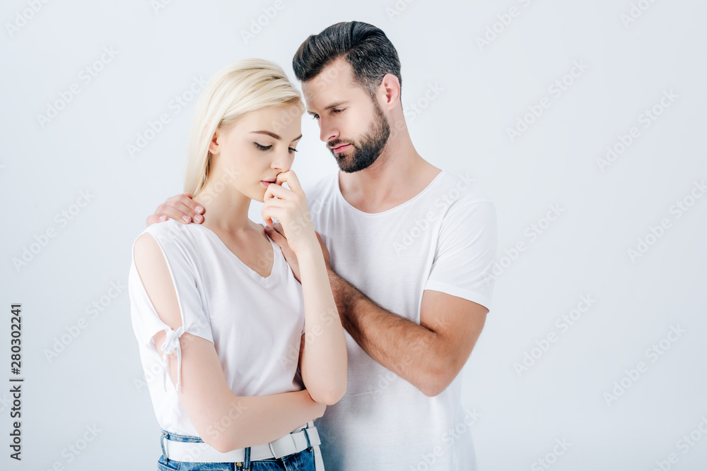 Naklejka premium handsome man embracing upset young woman isolated on grey