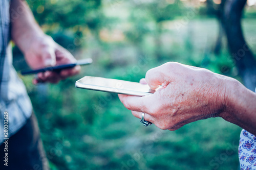 hands of elderly couple using smartphone for data transfer