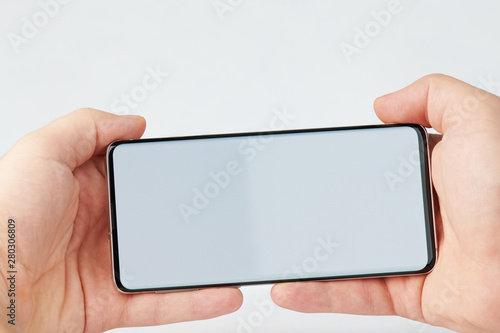 Hands hold smartphone horizontally