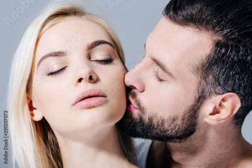 handsome man kissing beautiful girl isolated on grey