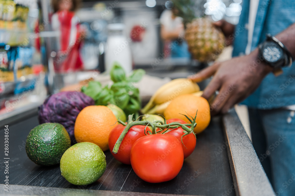 Φωτογραφία cropped view of african american man near supermarket counter with fruits and ve