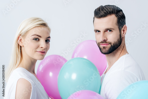 man and beautiful girl with balloons looking at camera isolated on grey © LIGHTFIELD STUDIOS