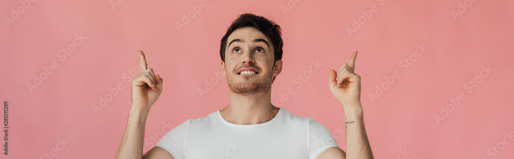 panoramic shot of smiling man looking up and showing idea signs isolated on pink panoramic shot of smiling man looking up and showing idea signs isolated on pink