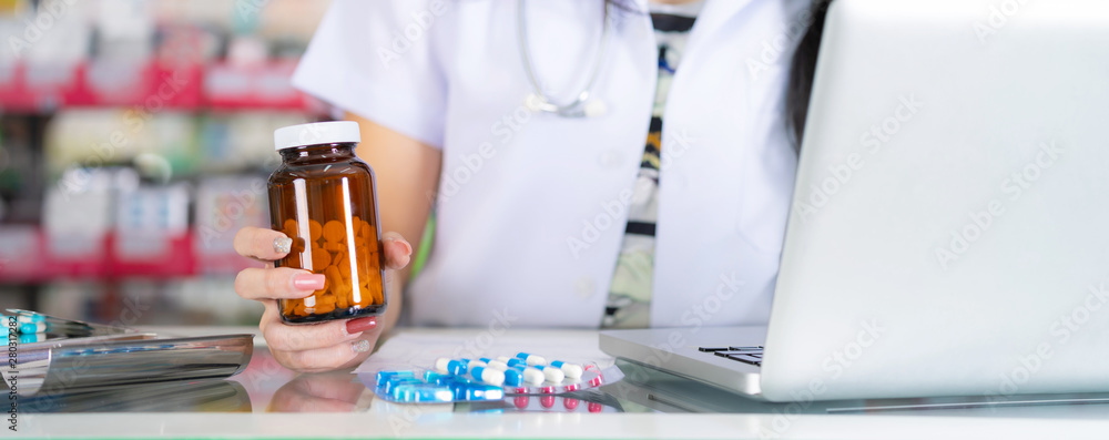 The pharmacist holds a bottle of medicine in the pharmacy The pharmacist holds a bottle of medicine in the pharmacy