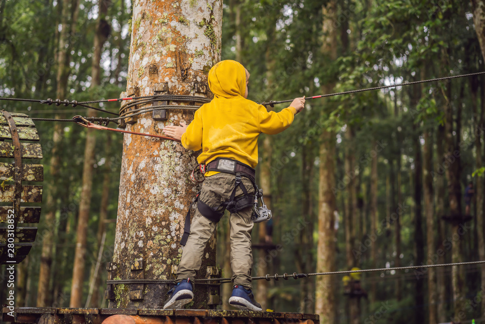 Little boy in a rope park. Active physical recreation of the child in the fresh air in the park. Training for children Little boy in a rope park. Active physical recreation of the child in the fresh air in the park. Training for children