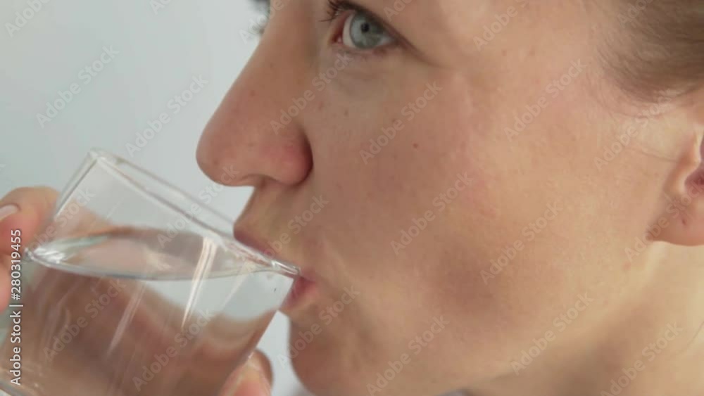 Woman swallows a pill of fish oil and drinks it down with water.