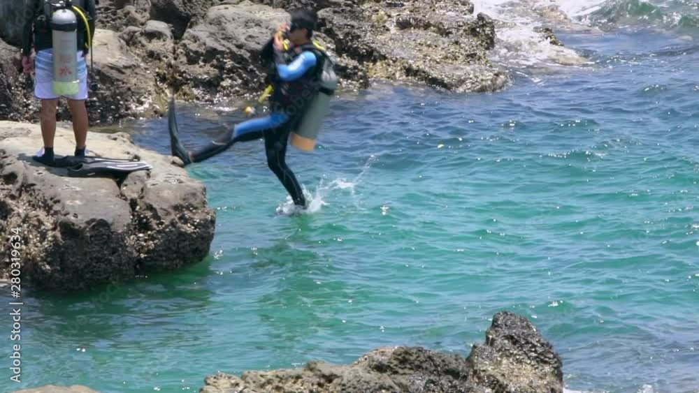 Slow Motion of scuba diver jumping in the water from rock of coast