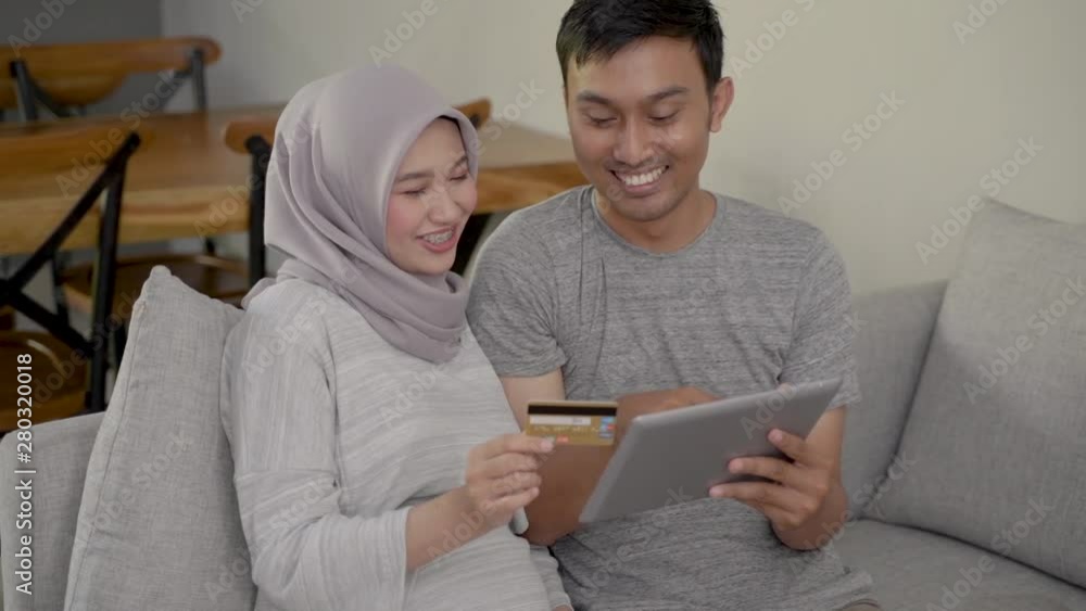 asian muslim couple buy and do payment using credit card while online shopping on market place asian muslim couple buy and do payment using credit card while online shopping on market place