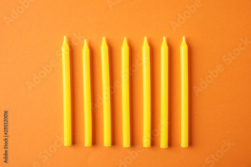 Yellow birthday candles on orange background  top view