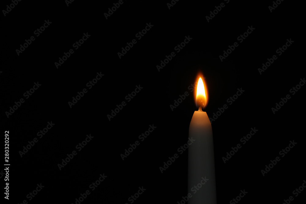 Burning candle on dark background, space for text. Symbol of sorrow Burning candle on dark background, space for text. Symbol of sorrow