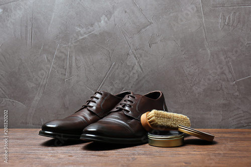 Foto Leather footwear and shoe shine kit on wooden surface, space for text