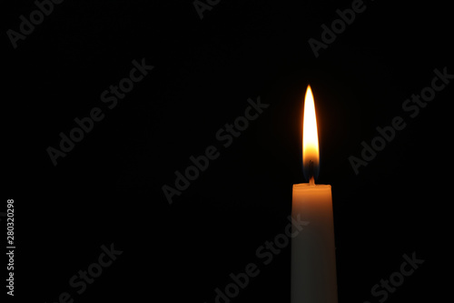 Burning candle on dark background, space for text. Symbol of sorrow