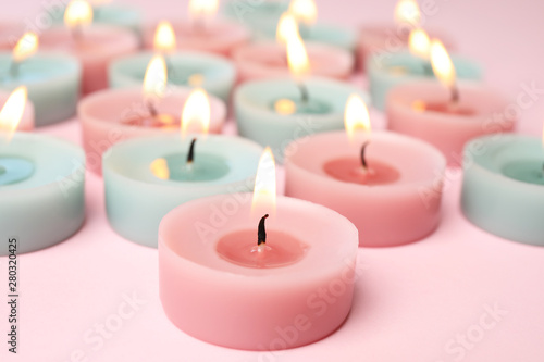 Burning colorful decorative candles on pink background, space for text