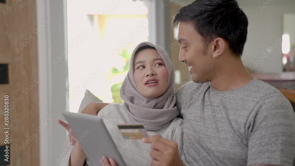 Couple shopping online watching on a tablet digital in the living room Couple shopping online watching on a tablet digital in the living room