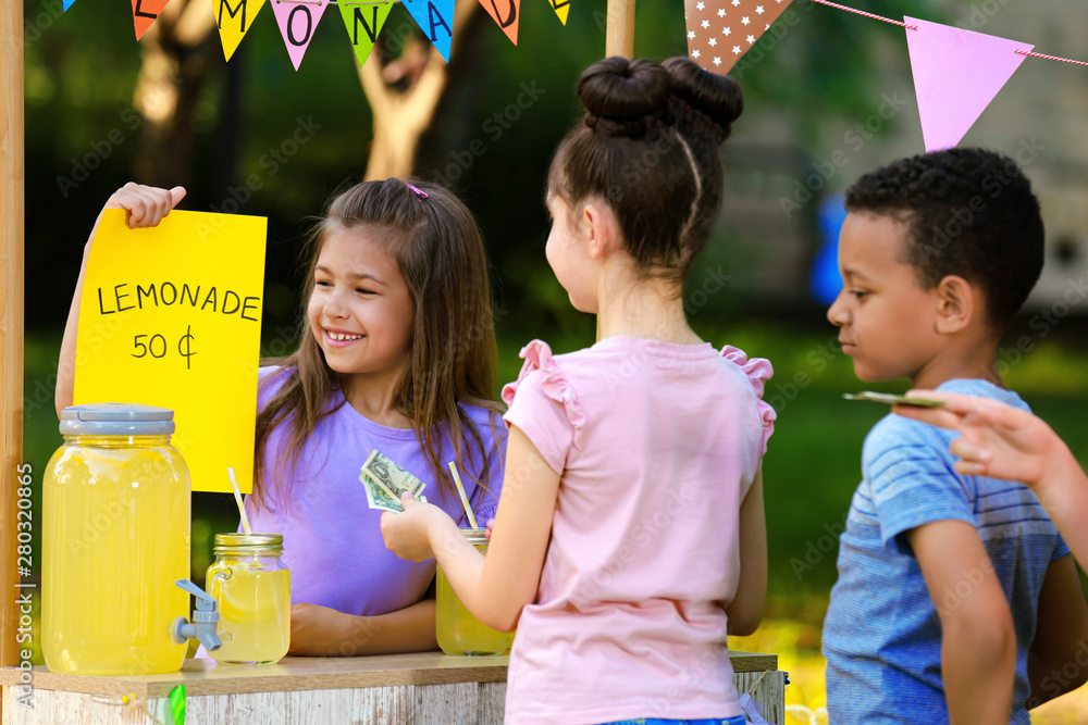 Little girl selling natural lemonade to kids in park. Summer refreshing