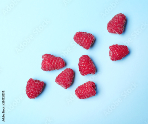 Flat lay composition with delicious ripe raspberries on blue background