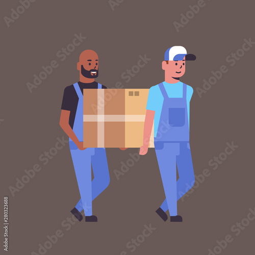 two couriers in uniform carrying cardboard box package mail express delivery service concept mix race workers holding parcel flat full length