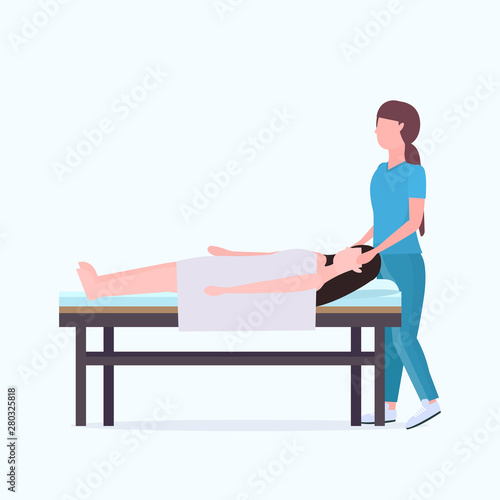 woman lying on massage bed african american masseuse therapist doing healing treatment massaging injured patient manual sport physical therapy rehabilitation concept full length