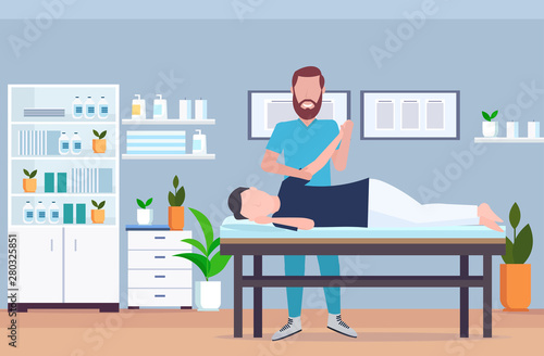 man patient lying on massage table therapist doing healing treatment massaging injured hand manual physical therapy rehabilitation concept full length modern hospital office interior horizontal