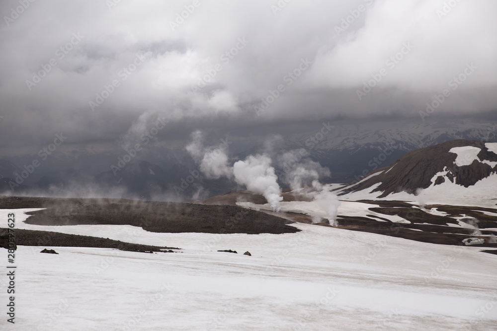 Fototapeta Geyser valley in Iceland. Icelandic summer, the earth is bursting with steam. Grey and white landscape with steam columns and dramatic sky background. Landmannalaugar, Iceland