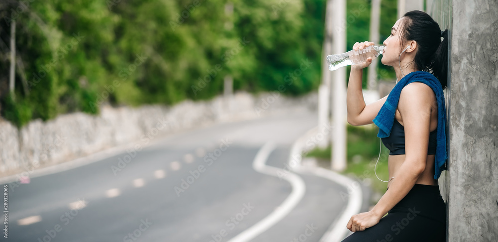 An beautiful Asian woman running and listening music over road during moring. Workout and sport outdoor concept.