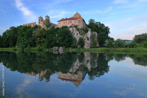 Benedictine abbey building beautifully located at top of rocky hill on Vistula river bank in Tyniec, nearby Krakow, Poland, reflections in water © Wioletta