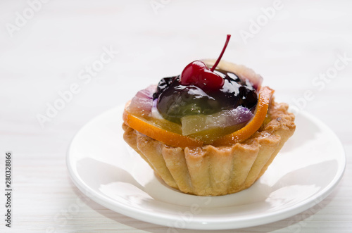 basket cake decorated with different fruit on white table photo