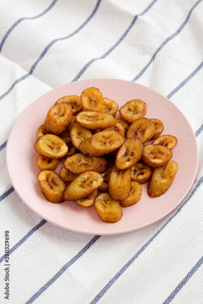 Homemade fried plantains on a pink plate, side view. Close-up. Homemade fried plantains on a pink plate, side view. Close-up.