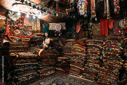 Girl in a carpet store. Happy woman customer choosing colored carpet in carpet store. Girl in Turkish market with amazing colorful carpets. Cheerful woman customer shopping carpet in interior store photo