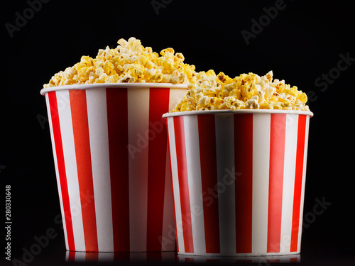 Paper striped buckets with popcorn isolated on black background