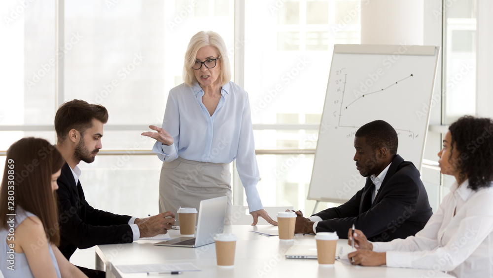 Angry mature businesswoman, boss scold employees for bad work results Angry mature businesswoman, boss scold employees for bad work results