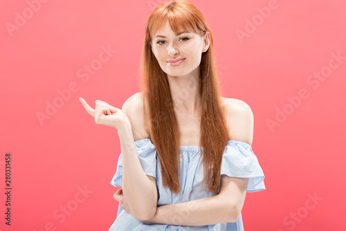 front view of smiling redhead girl looking at camera isolated on pink