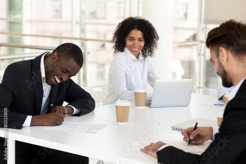 Excited African American worker signing contract at business meeting