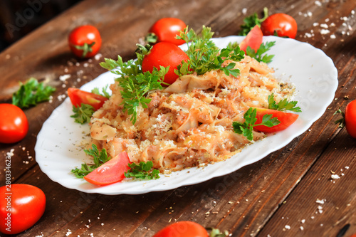 Italian cheese and tomato pasta meal covered with parmesan fresh tomato and parsley.