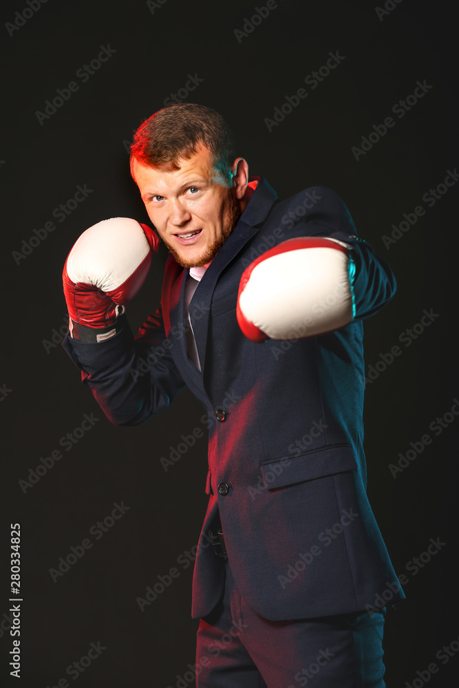 Businessman in boxing gloves against dark background