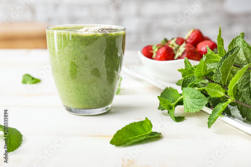 Glass of healthy smoothie, mint and strawberry on table