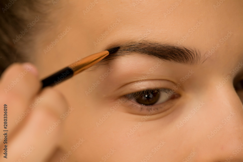 closeup of woman shaping her eyebrows with brush